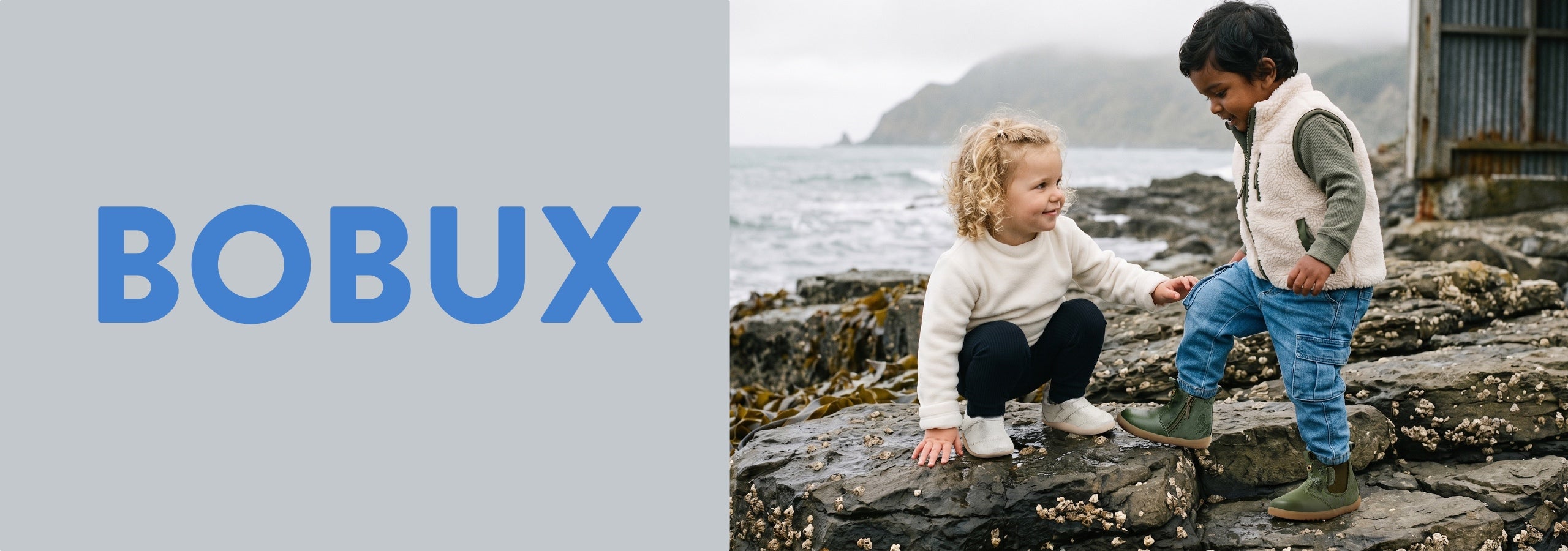 A split promotional image with the brand name BOBUX in large blue letters on a light gray panel on the left, and a lifestyle photo on the right showing two children outdoors on rocky coastal ground near the sea.